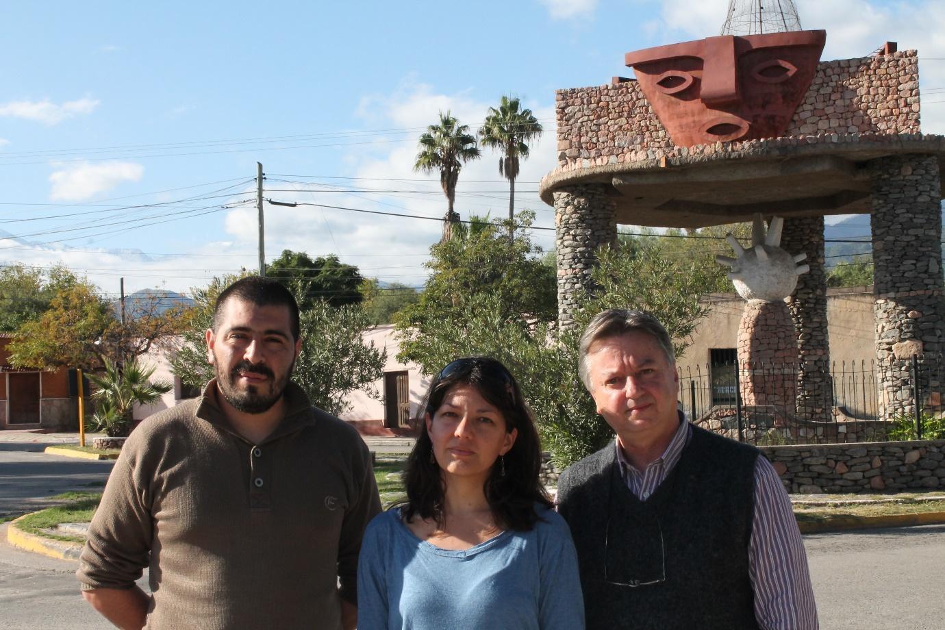 A group of people standing in front of a stone structure Description automatically generated